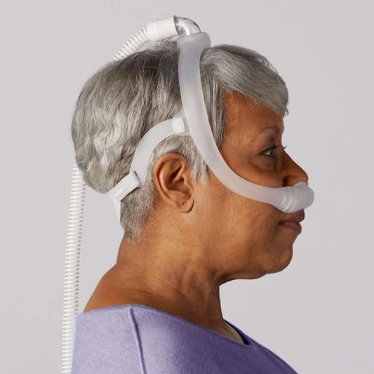 Side profile of the DreamWear nasal pillow mask being worn, with the hose rising from the crown of the head