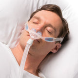 Photograph of a man asleep on a white pillow wearing the Nuance Pro nasal pillow mask