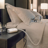 AirMini running on a hotel nightstand with the tube laid across the bed, room lit at night
