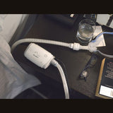 The AirMini on a bedside table at night, tubing coiled beside a glass of water and reading glasses