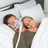 Couple sleeping peacefully in bed with man wearing ResMed AirTouch F20 full face CPAP mask during therapy