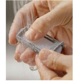 Hands rinsing a CPAP reusable foam filter pad clean under running water in a sink