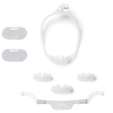 DreamWear nasal pillow mask in parts: the frame, three silicone cushions, headgear with arms, shown with two fabric wraps