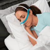 Woman sleeping on her side wearing the Evora nasal mask with the tube routed clear of the pillow
