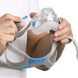 Hands holding ResMed AirFit F20 full face CPAP mask showing magnetic headgear clips and blue comfort pads