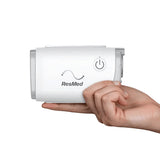 The ResMed AirMini resting on an open palm, showing that the whole machine fits in one hand