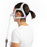 Back view of a woman wearing the AirTouch N20 For Her, showing the lavender headgear panels and gray straps