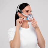 Photograph of a woman fitting the AirTouch F40, the cushion under her nose and a magnetic clip in her hand