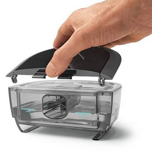 A hand lifting the lid off the DreamStation 2 water tank, showing the fill chamber and MAX line