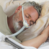 Man asleep in bed wearing the Solo nasal pillow mask with the tube running down over his shoulder