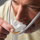 Close up of a man adjusting the Solo nasal pillows under his nose with one hand