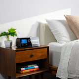 The React Health Luna G3 on a walnut nightstand beside a bed, its screen showing AutoCPAP mode
