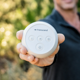A man holds the Transcend Micro out in one hand outdoors, its four buttons facing the camera
