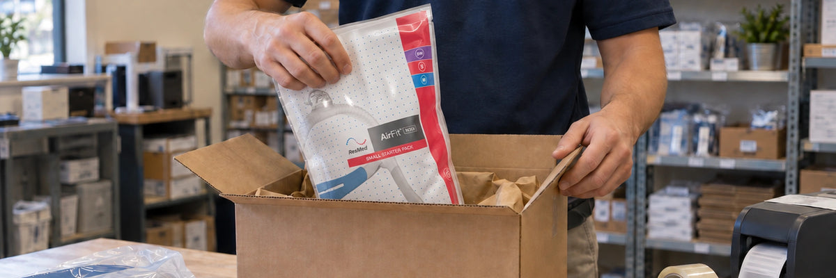 HME Medical team member packing a CPAP mask starter pack into a shipping box.